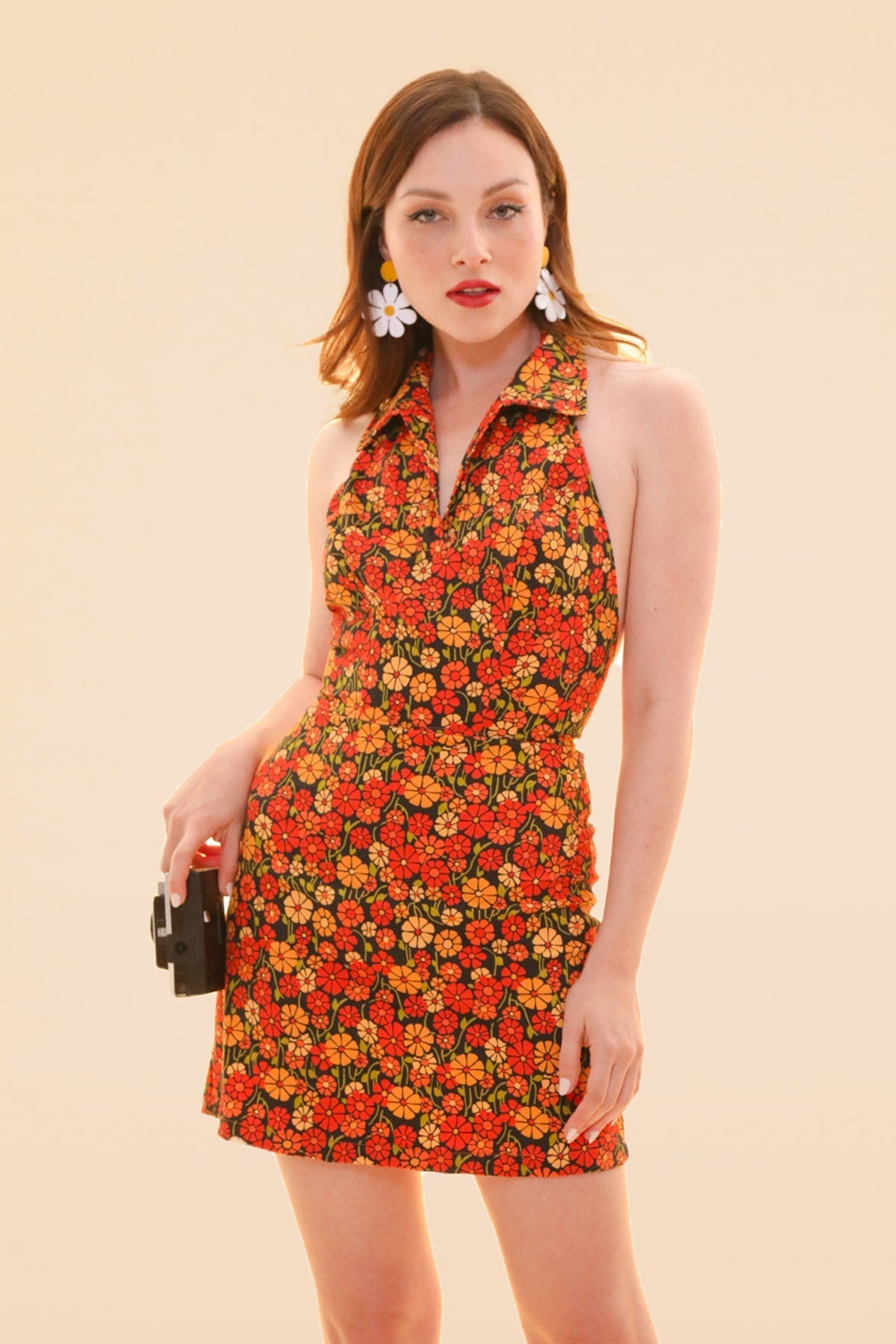 Woman modeling a colorful floral halter mini dress with a fitted waist and playful summer style from Miracle Eye New Arrivals by Miracle Eye