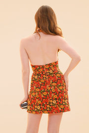 Miracle Eye floral halter mini dress with an open back shown from behind against a warm peach backdrop